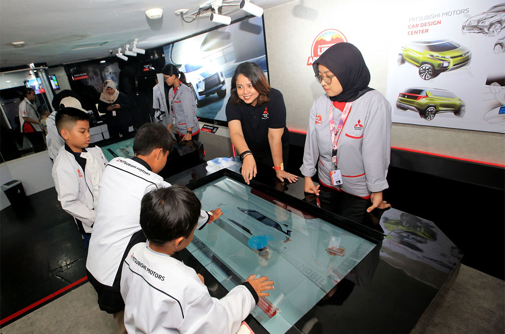 Intan Vidiasari MMKSI (baju hitam) menjelaskan perangkat lunak terbaru Mitsubishi Motors Car Design Center kepada anak-anak